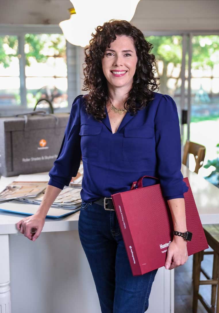 A professionally dressed woman holding a Hunter Douglas branded case posing for a photo